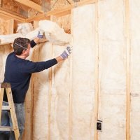 Construction Worker Insulating Wall with Fiberglass Batt